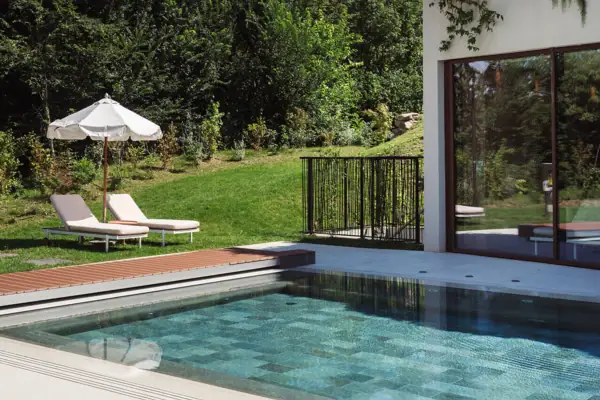 Ein Pool vor einem Gebäude mit Terrasse und Liegestühlen.