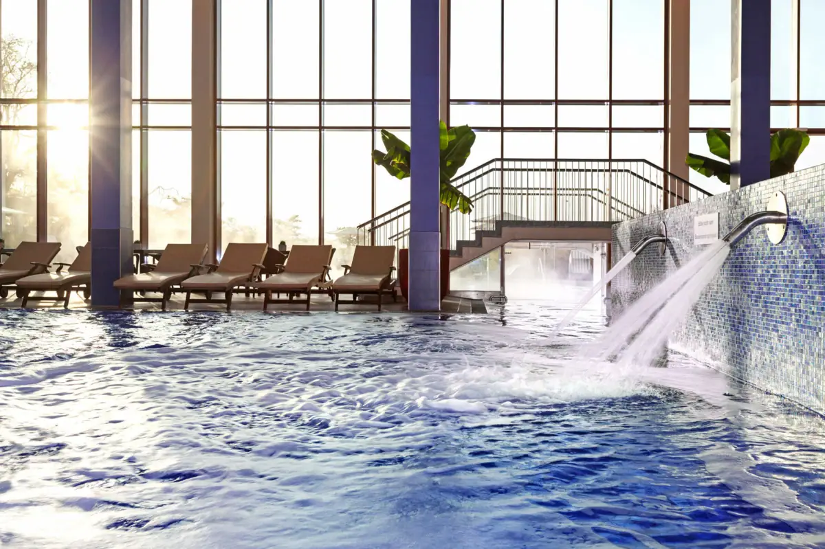 Innenpool Travemünde Ein Pool mit Schwallduschen und Liegestühlen im Hintergrund.