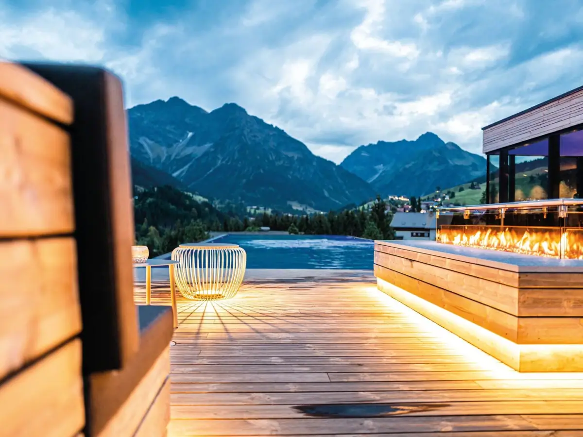 Eine Terrasse mit einem Feuer und einem Pool im Hintergrund.