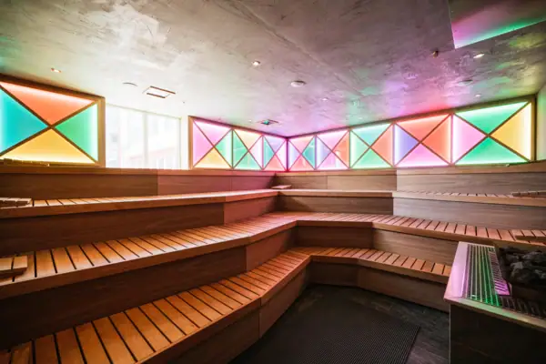 Eventsauna auf Sylt Eventsauna mit bunten Lichtern und Sitzbänken aus Holz.