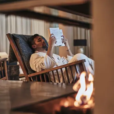 Ein Mann in einem weißen Bademantel liest ein Buch.