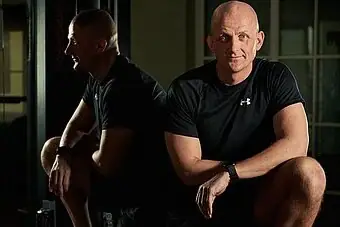 Ein Mann lehnt sich mit dem Rücken an.