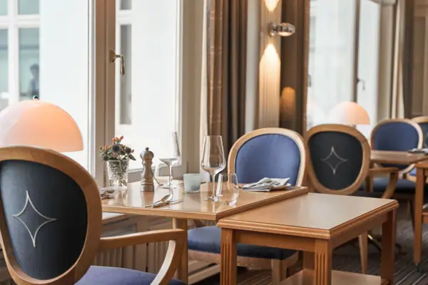 Ein Tisch mit Gläsern und einer Vase mit Blumen vor einem Fenster.