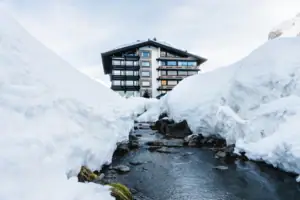 A-ROSA Hotel in Zürs Ein Gebäude am Fluss im Schnee.