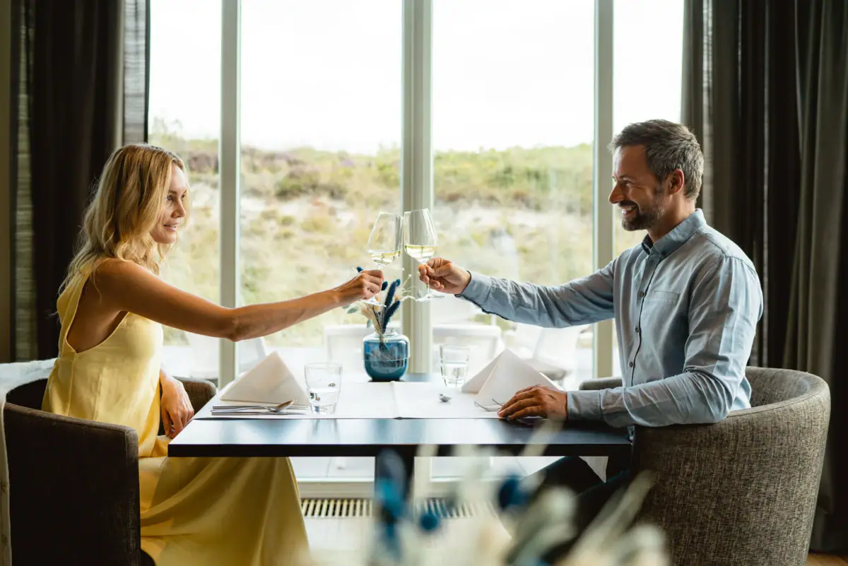 Ein Mann und eine Frau sitzen an einem Tisch mit Weingläsern.