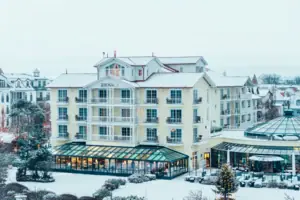 A-ROSA Ostseehotel Kühlungsborn Ein Gebäude im Schnee mit Bäumen im Hintergrund.