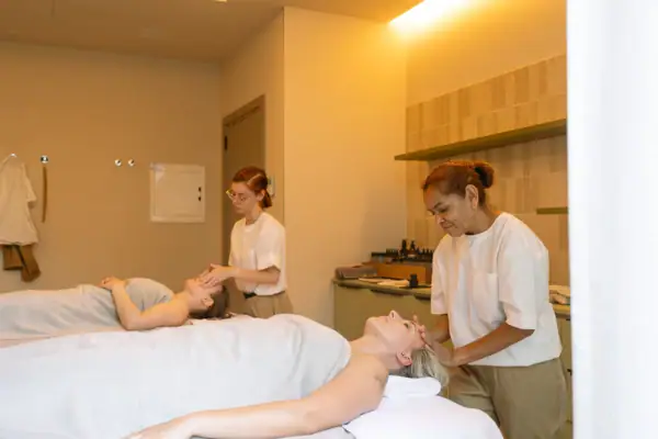 Entspannung im SPA Frauen genießen eine Massage, betreut von zwei Therapeutinnen im Wellnessbereich.