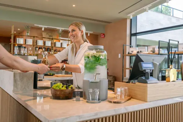 SPA Concierge im A-ROSA Gardasee Mitarbeiterin am SPA Concierge im A-ROSA Gardasee berät Gäste zu Anwendungen und Behandlungen und überreicht ein Getränk.