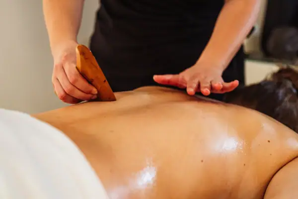 Rückenmassage Eine Person massiert mit einem Massagegerät den Rücken einer anderen Person.