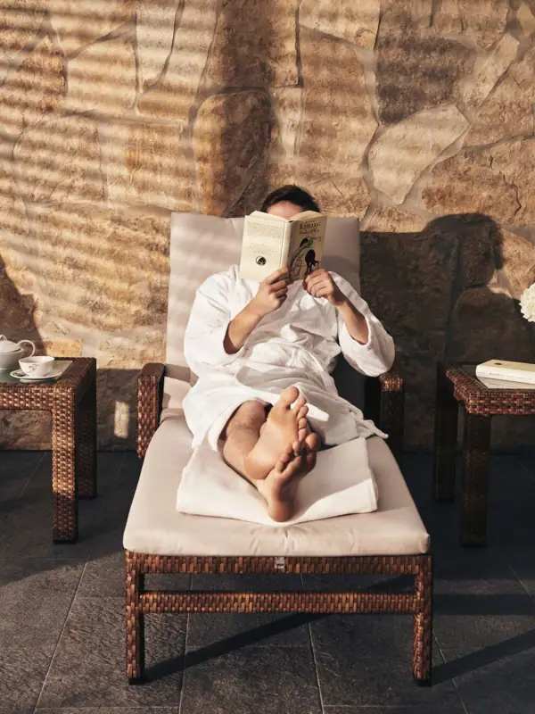 Eine Person liest ein Buch auf einem Liegestuhl.