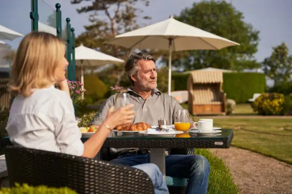 Ein Mann und eine Frau sitzen an einem Tisch im Freien.