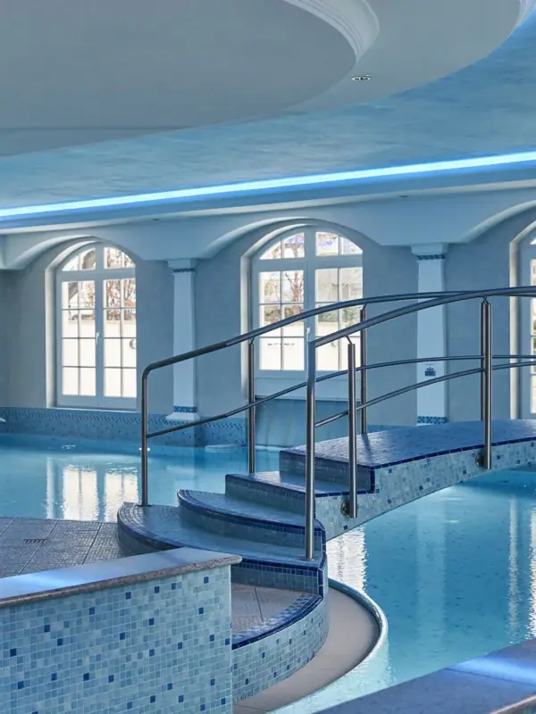 Schwimmbad mit geschwungenem Gehweg im Innenbereich.