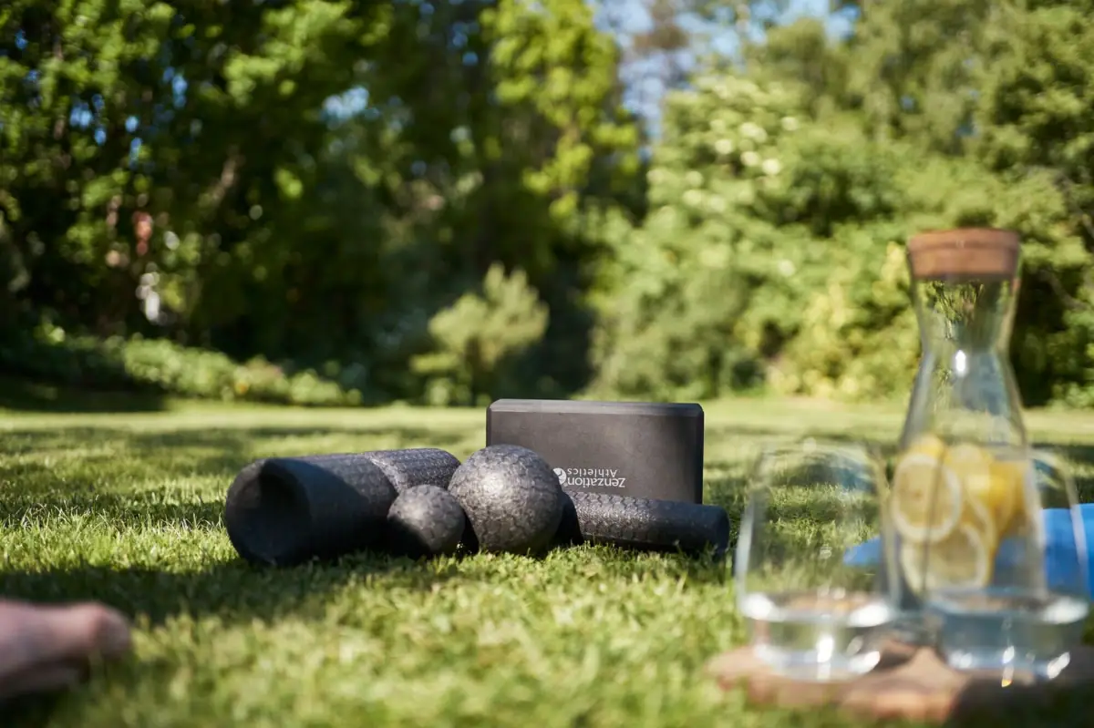 Yogamatten und ein Glas Wasser auf Gras