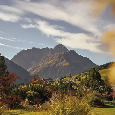 Landschaft eines Gebirges mit Wolken am Himmel und Pflanzen im Vordergrund.
