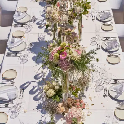 Hochzeit Kurhaus Binz Ein für eine Dinnerparty oder Hochzeit gedeckter Tisch mit Tischwäsche, Geschirr und Blumenvasen als Mittelstück.