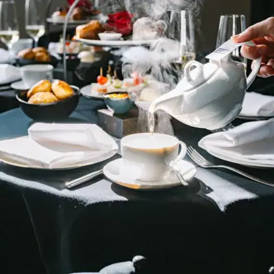 Eine Person gießt Tee in eine Tasse ein.