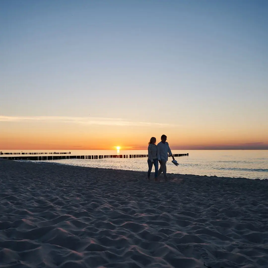 Ein Paar spaziert am Strand entlang.