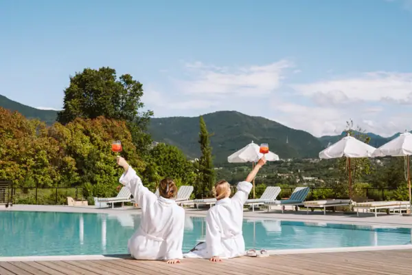 Gäste genießen Aperitivo an der Poolbar des A-ROSA Gardasee Zwei Personen stoßen mit Aperitivo-Gläsern am Pool des A-ROSA Gardasee an