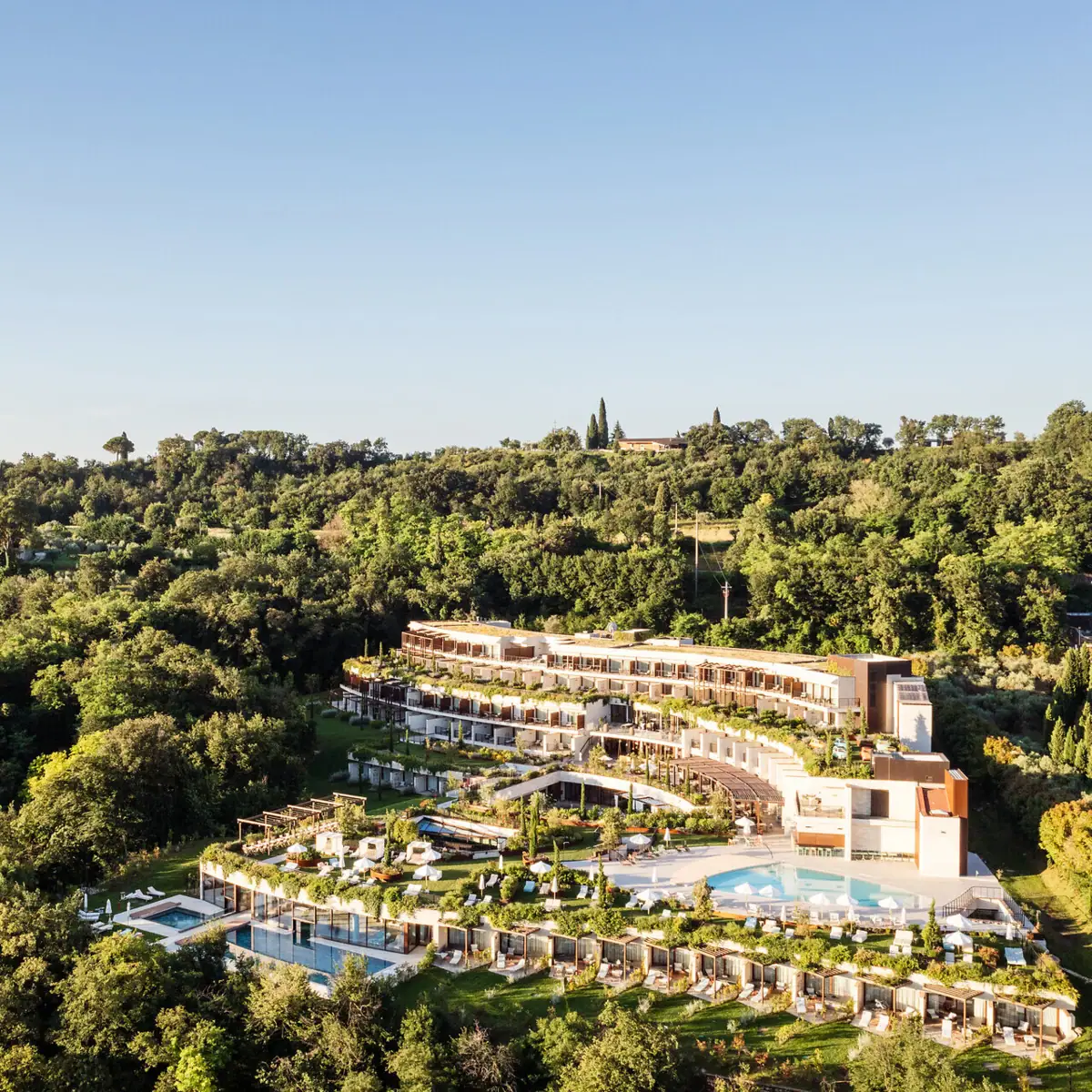 A-ROSA Gardasee inmitten mediterraner Hügellandschaft Luftaufnahme des A-ROSA Gardasee Hotels, eingebettet in grüne Hügellandschaft mit Poolanlage und Panoramablick auf den See.