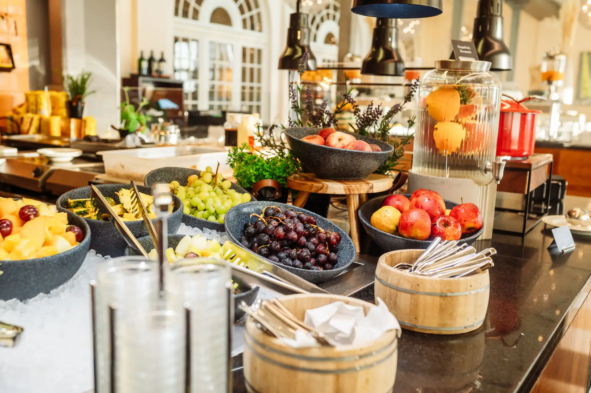 Buffet mit Obst Ein Tisch mit Schalen voller Obst und Besteck.