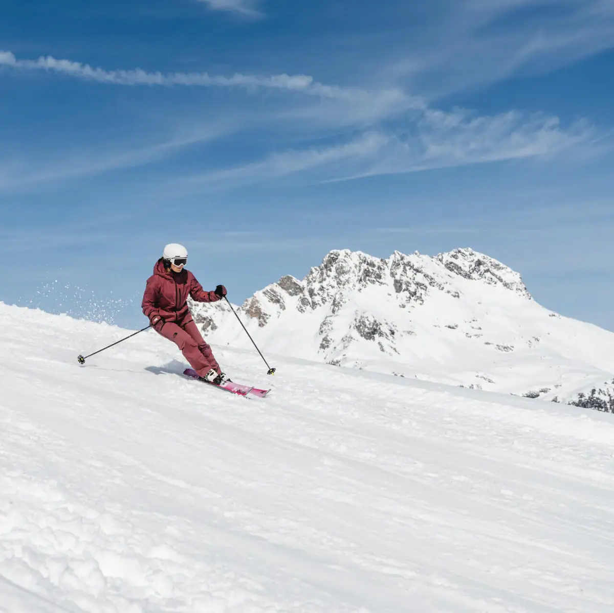 Eine Person fährt auf Skiern einen verschneiten Berg hinunter.