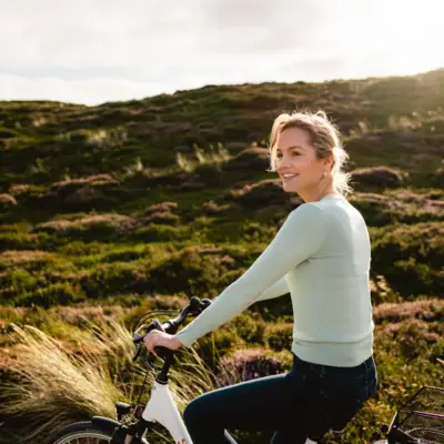 Eine Frau fährt Fahrrad in einer grasbewachsenen Gegend.