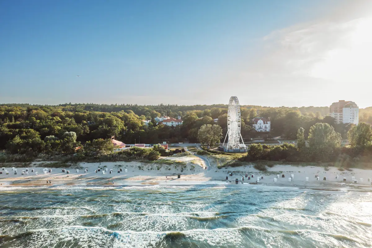 Strand mit Riesenrad und Bäumen im Hintergrund.