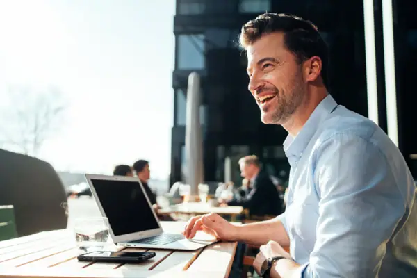 Business Ein Mann sitzt an einem Tisch mit einem Laptop.