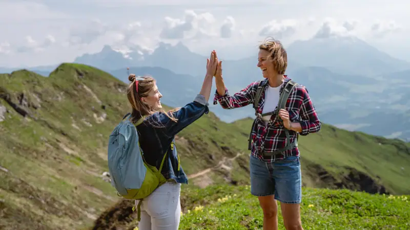 Highfive Berge Zwei Frauen geben sich in den Bergen ein High Five.