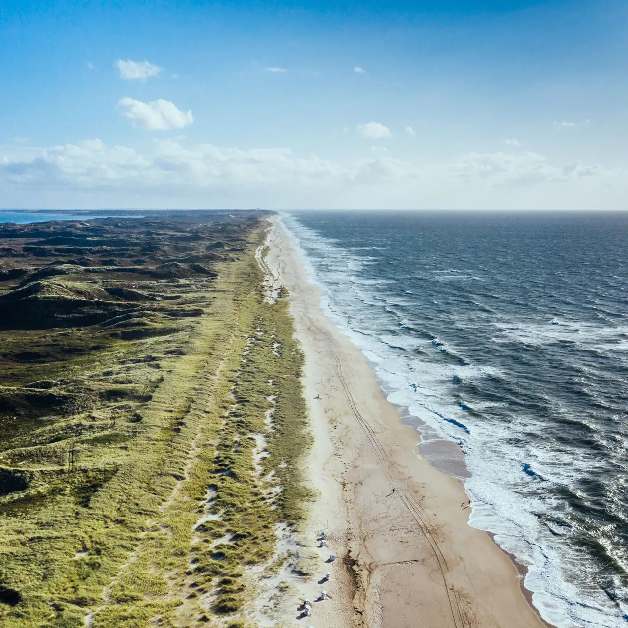 Langer Strand mit brechenden Wellen