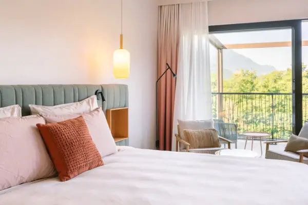 Modernes Doppelzimmer im A-ROSA Gardasee Elegant eingerichtetes Hotelzimmer mit Doppelbett, sanften Farben und Balkon mit Ausblick ins Grüne.