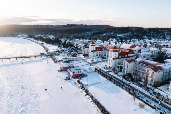 Kurhaus Binz im Winter Schneebedeckte Stadt mit Gebäuden und einer Brücke.