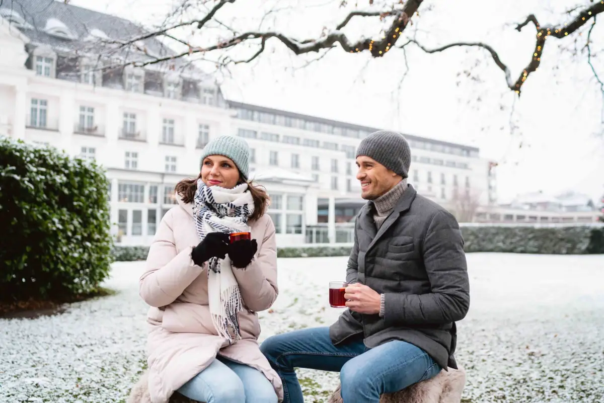 Ein Mann und eine Frau sitzen auf einer verschneiten Bank.