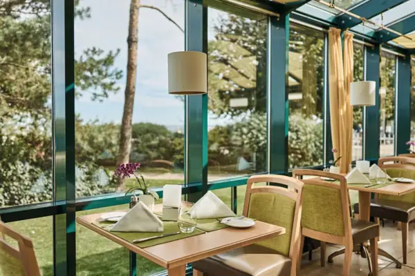 Ein Tisch mit Stühlen und Servietten in einem Raum mit Fenstern.