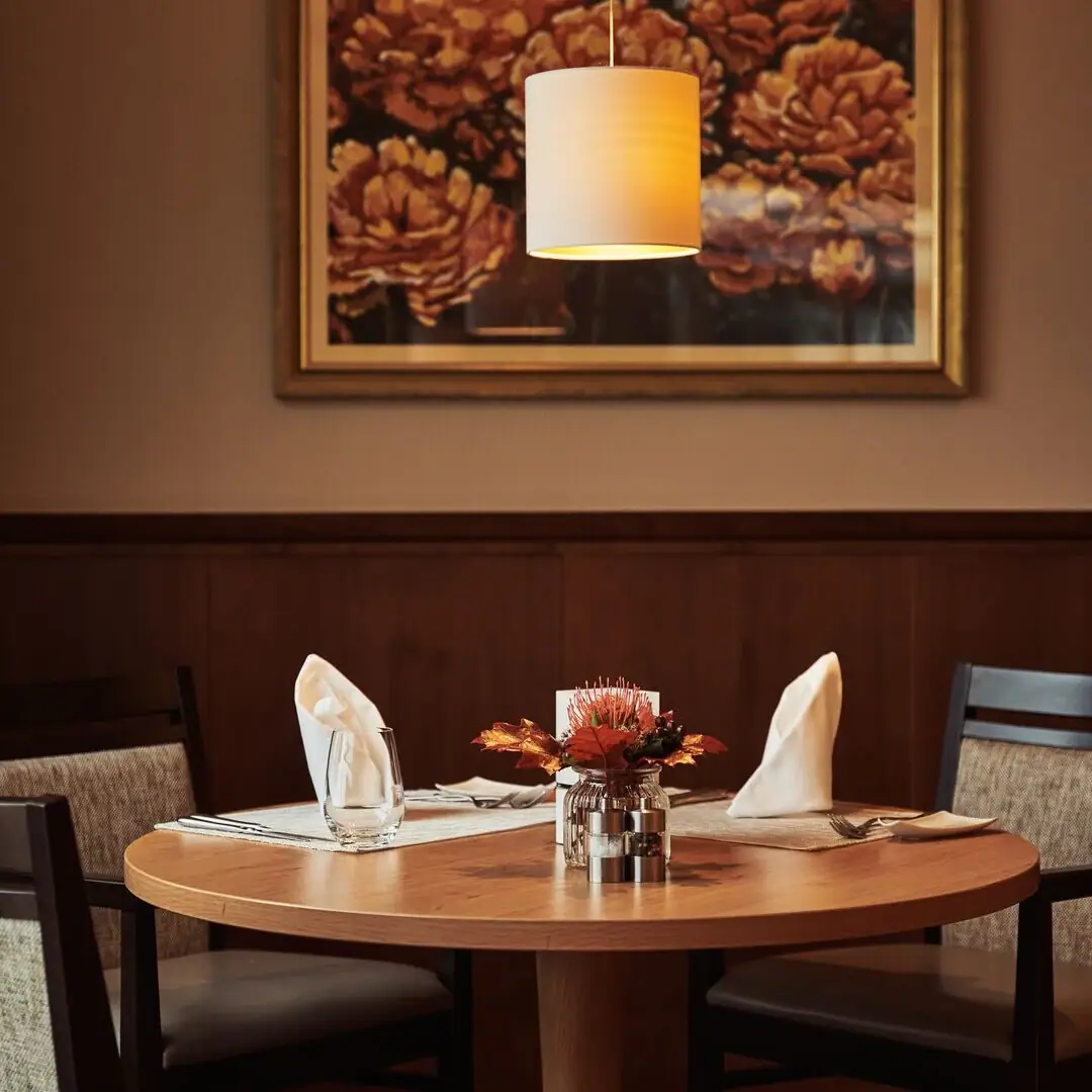 Ein Tisch mit einer Lampe und einem Blumenarrangement darauf.