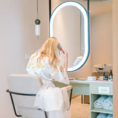 Herrichten im A-ROSA Gardasee Eine Frau im Bademantel kämmt sich die Haare vor einem Spiegel.