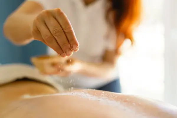 Eine Person streut Salz auf den Rücken einer anderen Person.