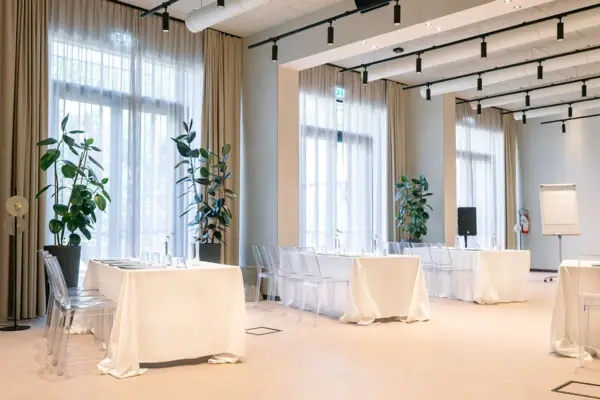 Moderner Eventraum für Ihre Feier Heller Indoor-Eventraum mit gedeckten Tischen und großen Fenstern für Hochzeitsfeiern.