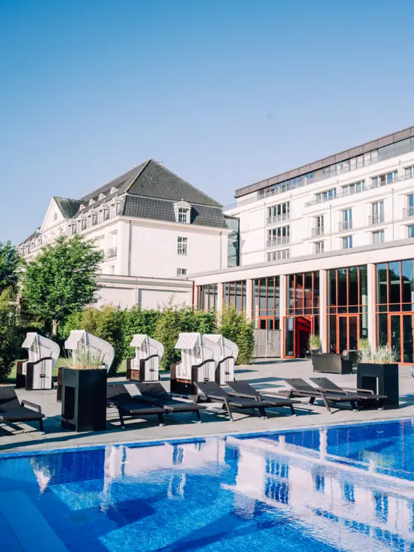 SPA-ROSA Travemünde Ein Swimmingpool mit Liegestühlen und einem Gebäude im Hintergrund.