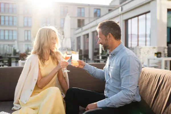 Sommerterrasse Ein Mann und eine Frau sitzen auf einem Sofa und halten Getränke.