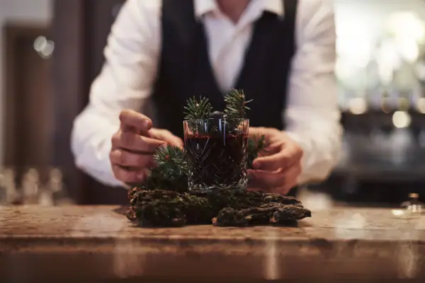 Signature Cocktail: Forest Flair. Eine Person hält ein Glas mit einem Getränk.