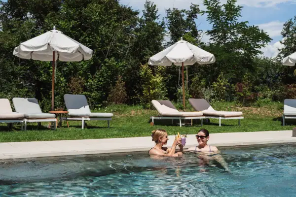 Freunde entspannen gemeinsam am Pool des A-ROSA Gardasee Zwei Gäste stoßen im Pool des A-ROSA Gardasee mit Getränken an