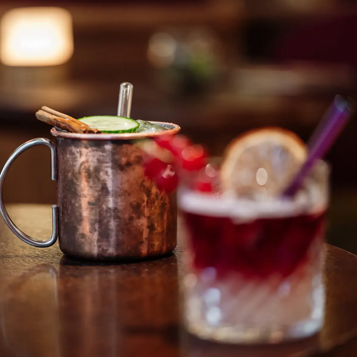 Kupferbecher mit Gurkenscheibe und Strohhalm auf einem Tisch