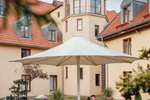 Dachterrasse Eine Frau sitzt an einem Tisch unter einem Sonnenschirm im Innenhof.
