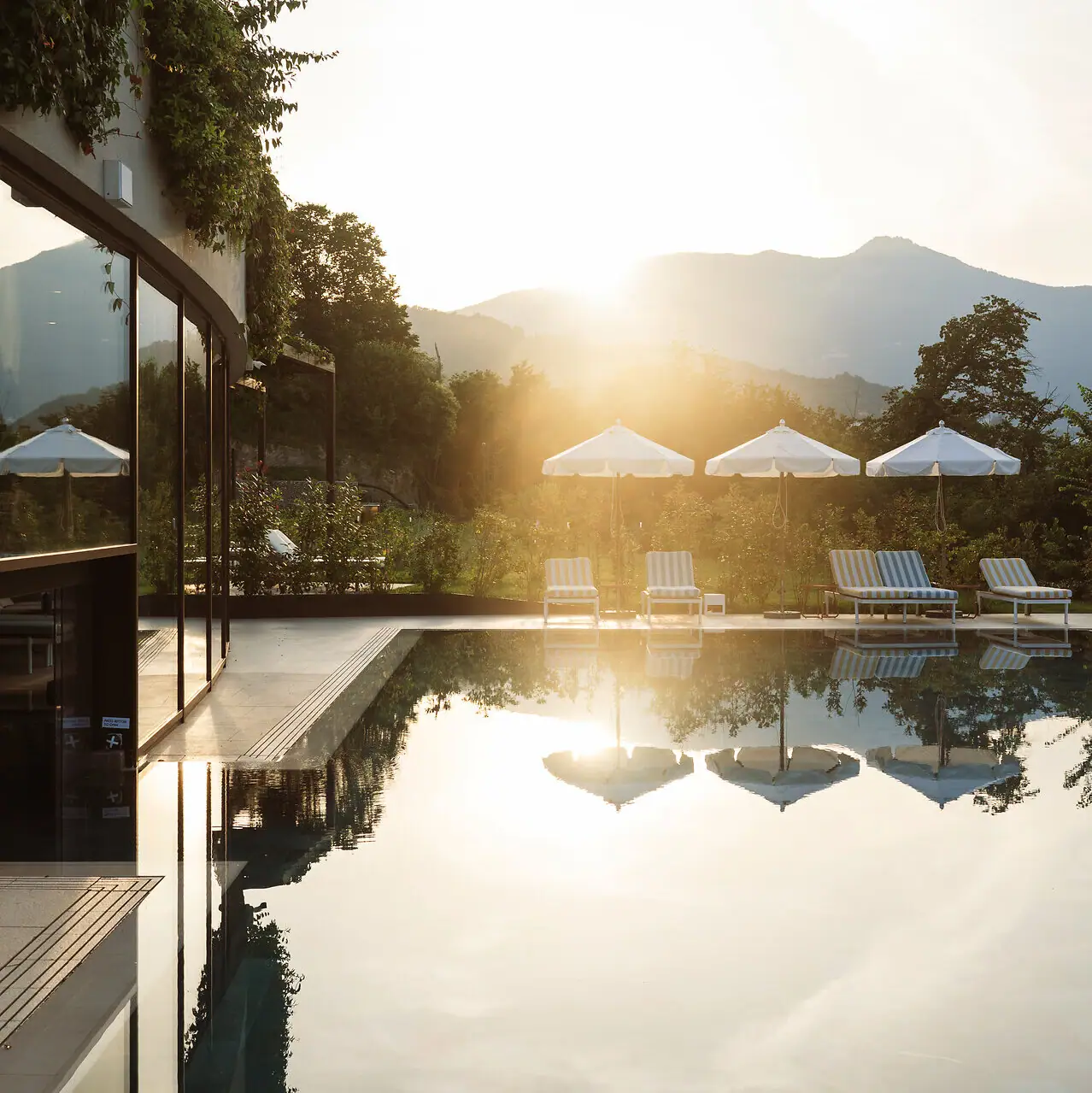 Ein Pool mit Liegestühlen und Sonnenschirmen vor einem Gebäude.