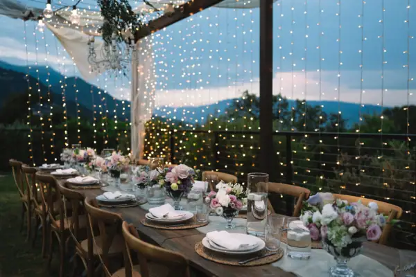 Outdoor-Setup bei Nacht im A-ROSA Gardasee Festlich gedeckte Hochzeitstafel im Freien bei Nacht mit Lichterketten.