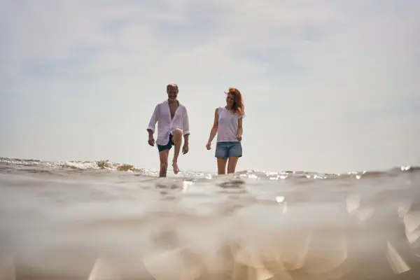 Ein Mann und eine Frau gehen im Wasser spazieren.