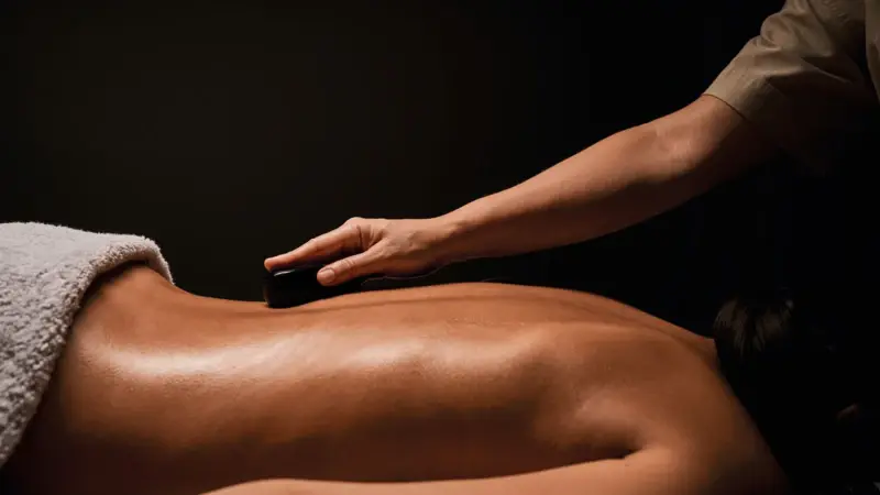 Wellnessmomente Eine Detailaufnahme eines Rückens, der mit Hot Stone behandelt wird