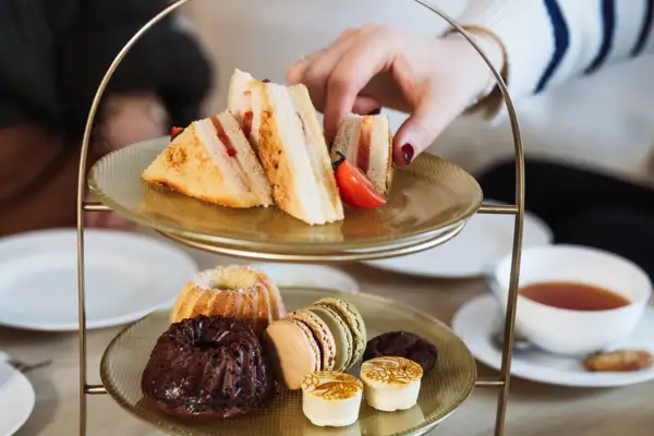Hand greift nach einem Sandwich auf einem Teller
