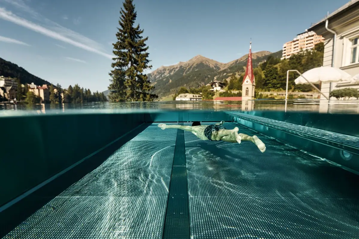 Eine Person schwimmt in einem Außenpool.